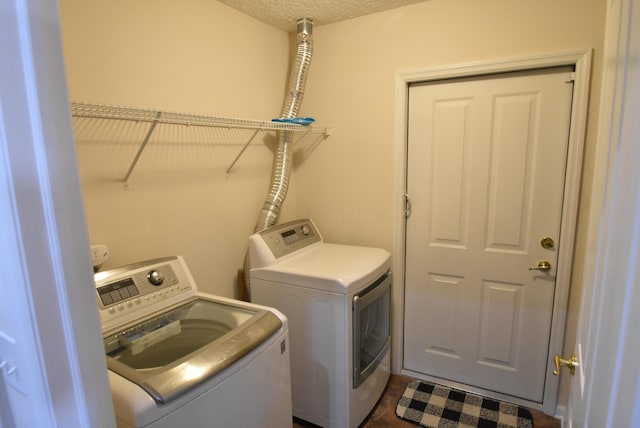 laundry area with washing machine and dryer and a textured ceiling