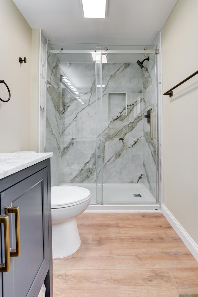 bathroom featuring vanity, hardwood / wood-style flooring, toilet, and a shower with shower door