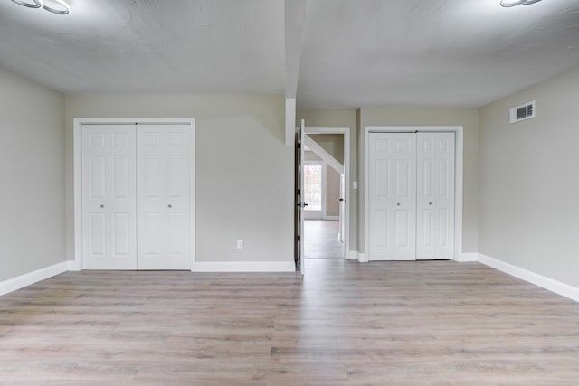 unfurnished bedroom with multiple closets and light hardwood / wood-style flooring