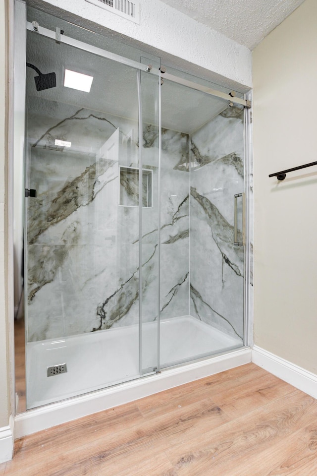 bathroom with wood-type flooring, a textured ceiling, and an enclosed shower