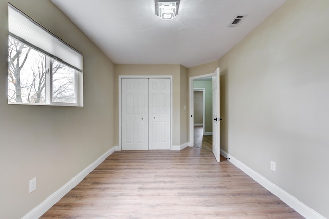 unfurnished bedroom with light hardwood / wood-style flooring and a closet