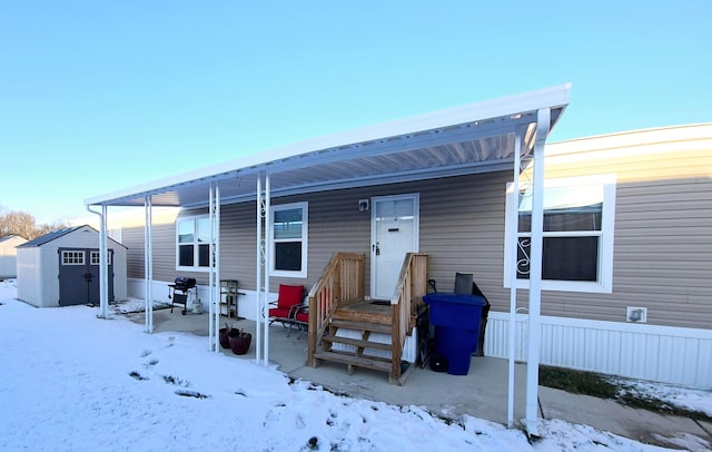 snow covered rear of property with a storage shed