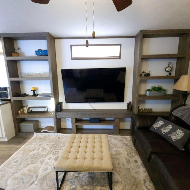 living room featuring built in features, ceiling fan, and light hardwood / wood-style flooring