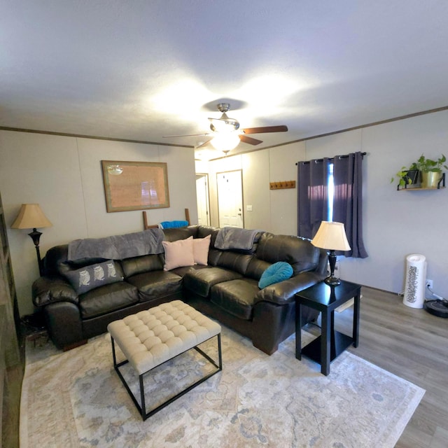 living room featuring hardwood / wood-style flooring, ornamental molding, and ceiling fan