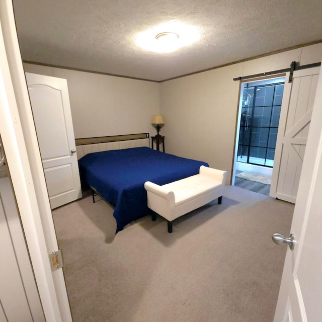 carpeted bedroom with a barn door and a textured ceiling