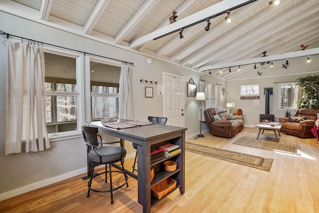 dining space with wood ceiling, a wood stove, hardwood / wood-style floors, and lofted ceiling with beams