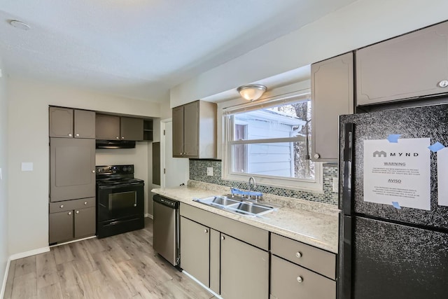 kitchen featuring tasteful backsplash, light hardwood / wood-style floors, sink, and black appliances