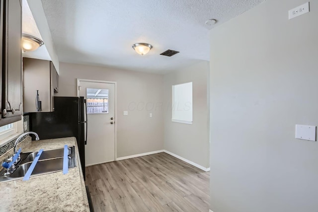 kitchen with sink, a textured ceiling, and light hardwood / wood-style floors