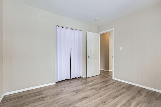 unfurnished bedroom featuring wooden walls and light hardwood / wood-style floors