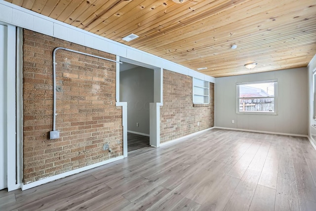 empty room with wood ceiling, hardwood / wood-style flooring, built in shelves, and brick wall