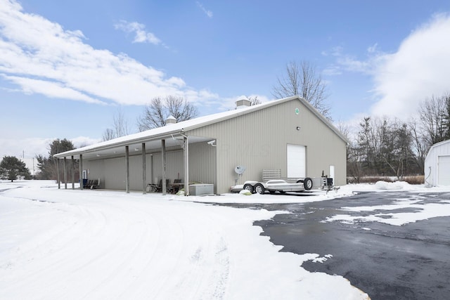 snow covered back of property featuring a garage and an outbuilding