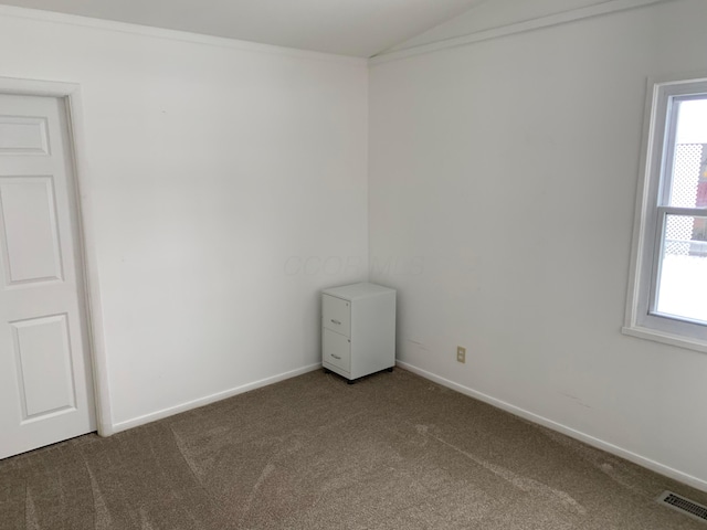 empty room with vaulted ceiling, plenty of natural light, crown molding, and dark carpet