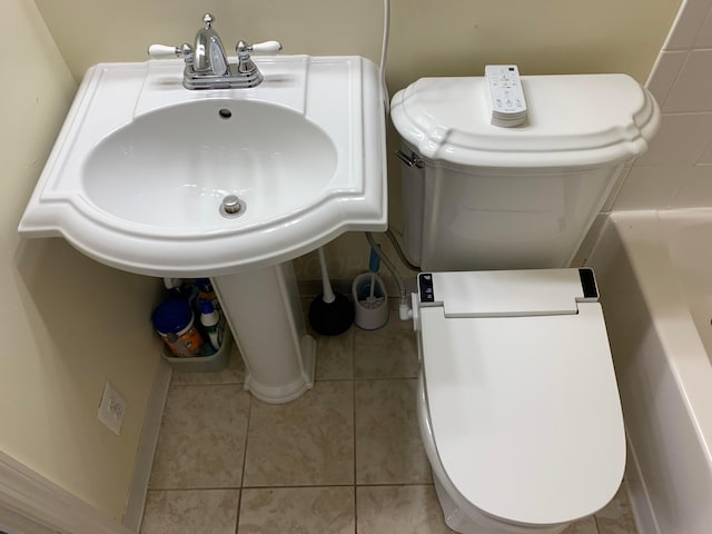 bathroom featuring tile patterned flooring, a tub to relax in, and toilet