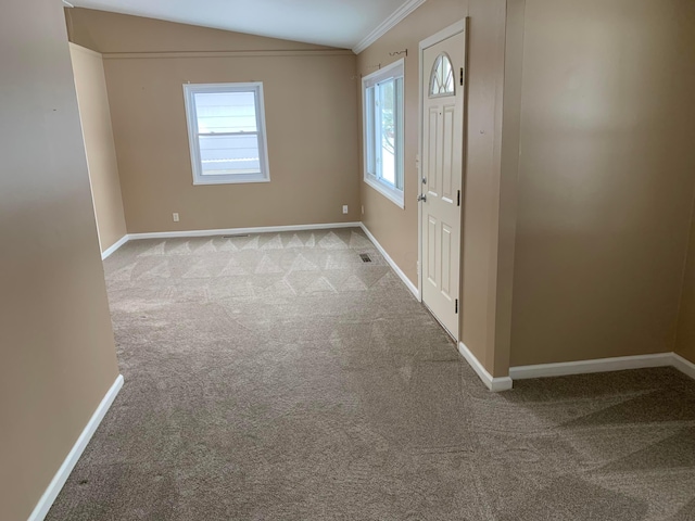 entrance foyer featuring light colored carpet, lofted ceiling, ornamental molding, and a wealth of natural light