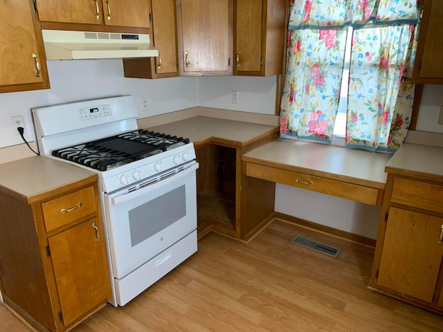 kitchen featuring built in desk, white range with gas stovetop, and light hardwood / wood-style floors