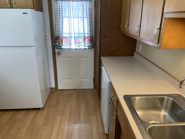 kitchen with sink, white appliances, and light wood-type flooring