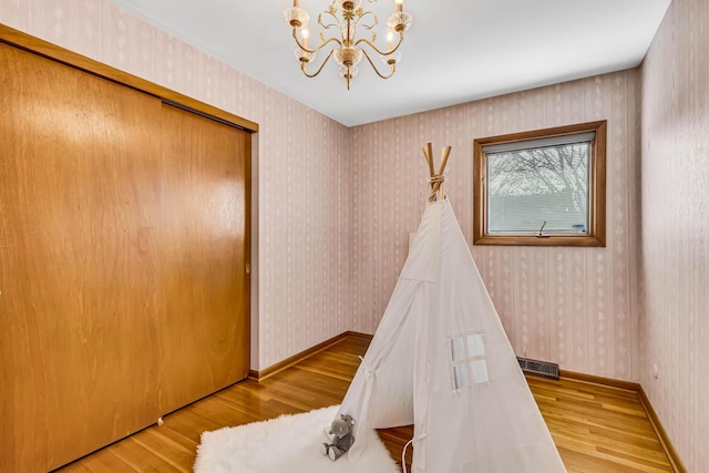 playroom featuring an inviting chandelier and light hardwood / wood-style flooring