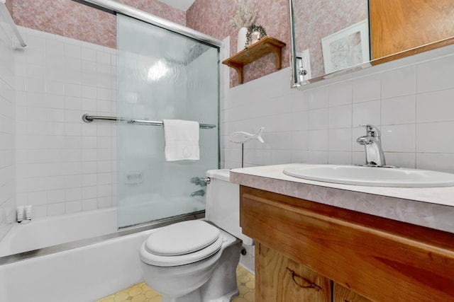 full bathroom with vanity, tile walls, shower / bath combination with glass door, and toilet