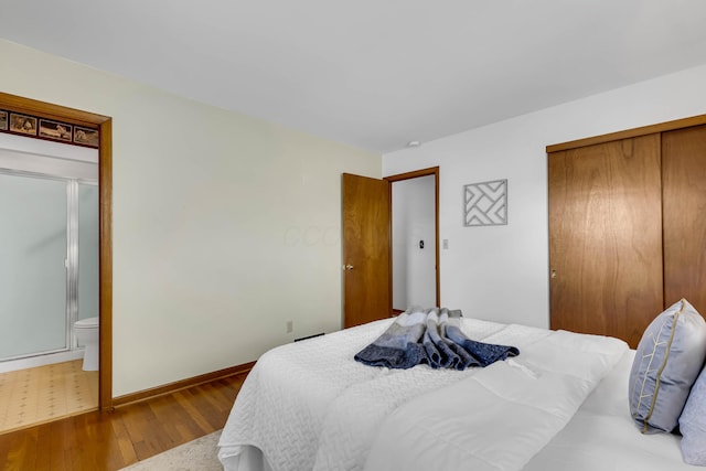 bedroom featuring hardwood / wood-style flooring, ensuite bath, and a closet