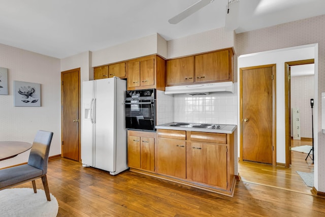 kitchen featuring tasteful backsplash, white refrigerator with ice dispenser, dark hardwood / wood-style floors, and black oven