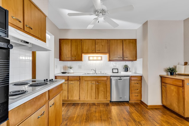 kitchen featuring dark hardwood / wood-style floors, electric cooktop, dishwasher, sink, and decorative backsplash