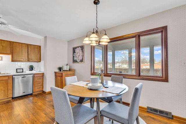 dining area with hardwood / wood-style flooring and ceiling fan with notable chandelier