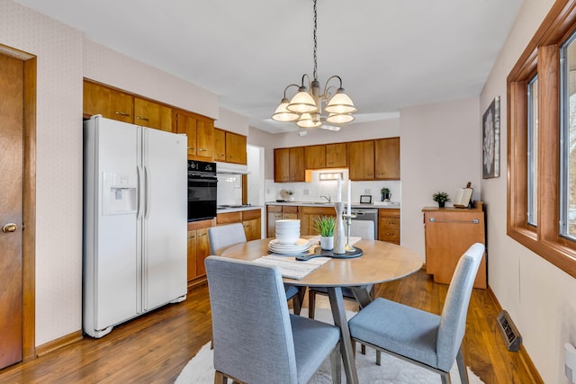 dining space with dark wood-type flooring, a chandelier, and sink