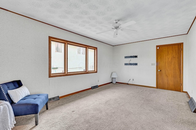 living area featuring ceiling fan, carpet flooring, crown molding, and a textured ceiling