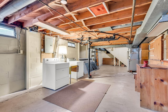 basement featuring washing machine and dryer, heating unit, and electric panel