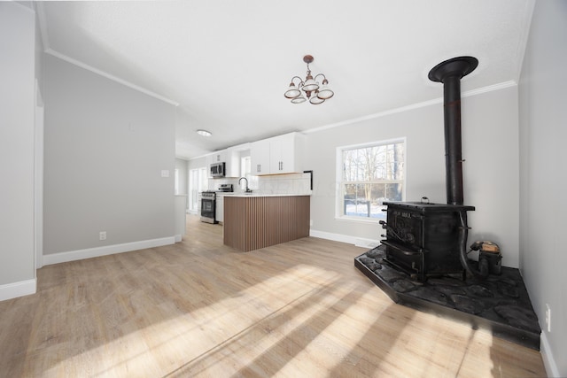 kitchen featuring sink, a notable chandelier, appliances with stainless steel finishes, white cabinets, and ornamental molding