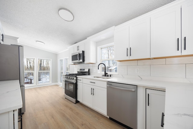 kitchen with decorative backsplash, white cabinets, light stone countertops, and appliances with stainless steel finishes