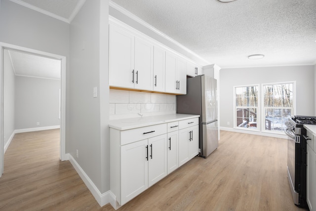 kitchen featuring white cabinets, light hardwood / wood-style floors, crown molding, and appliances with stainless steel finishes