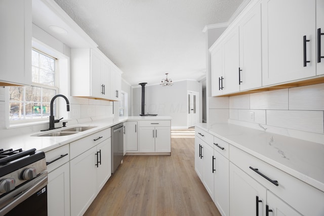 kitchen featuring appliances with stainless steel finishes, light wood-type flooring, tasteful backsplash, sink, and white cabinetry