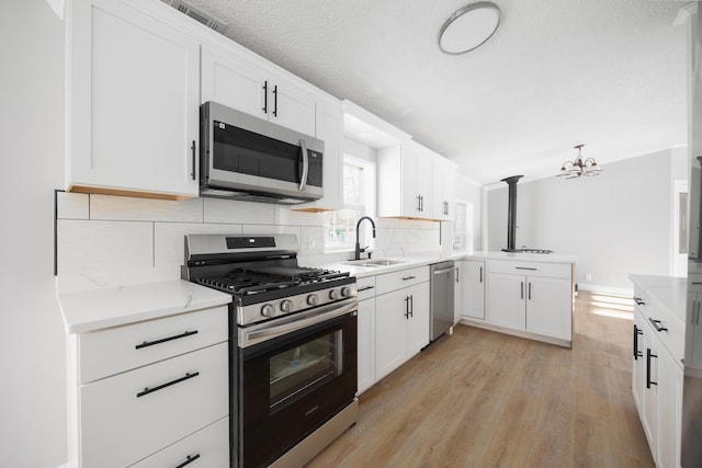 kitchen with tasteful backsplash, sink, white cabinets, and appliances with stainless steel finishes