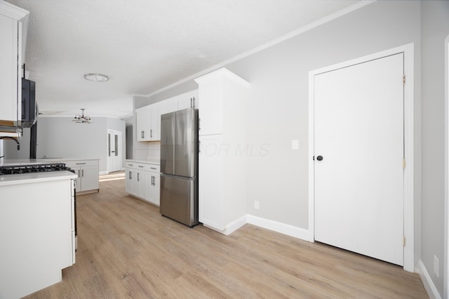 kitchen with white cabinets, light hardwood / wood-style floors, stainless steel refrigerator, and ornamental molding