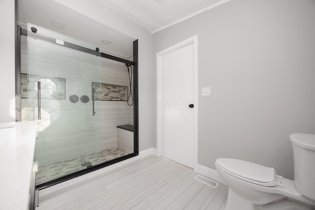 bathroom with a textured ceiling, toilet, and a shower with door