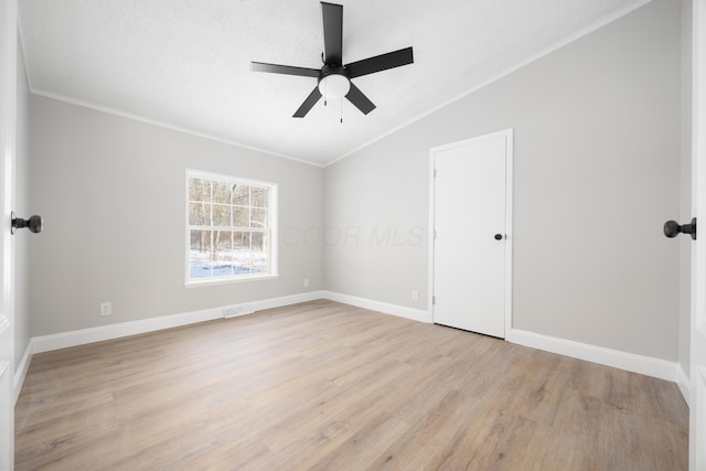 unfurnished room with ceiling fan, light hardwood / wood-style floors, a textured ceiling, vaulted ceiling, and ornamental molding