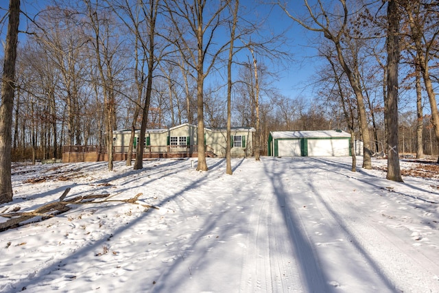 snowy yard with a garage and an outdoor structure