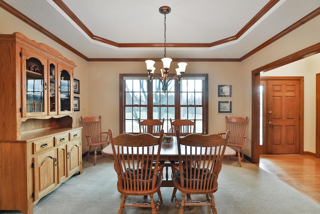 dining area with ornamental molding, a chandelier, and a tray ceiling