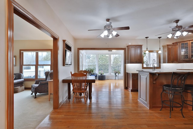 kitchen featuring pendant lighting, a kitchen breakfast bar, kitchen peninsula, and light wood-type flooring