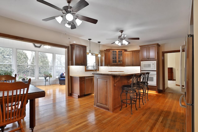 kitchen featuring stainless steel appliances, a center island, light hardwood / wood-style floors, and decorative light fixtures