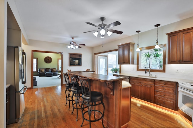 kitchen featuring sink, appliances with stainless steel finishes, hanging light fixtures, backsplash, and a center island