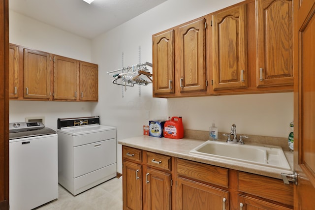 clothes washing area with washer and dryer, sink, and cabinets