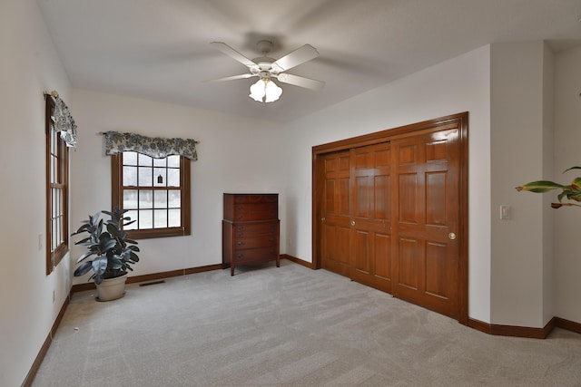 unfurnished bedroom with ceiling fan, a closet, and light carpet