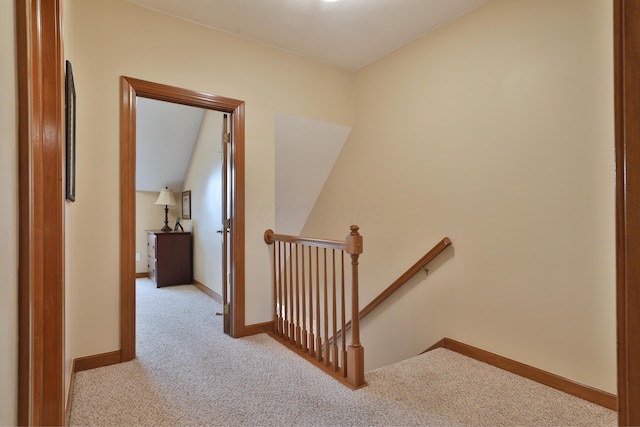 hallway with vaulted ceiling and light colored carpet