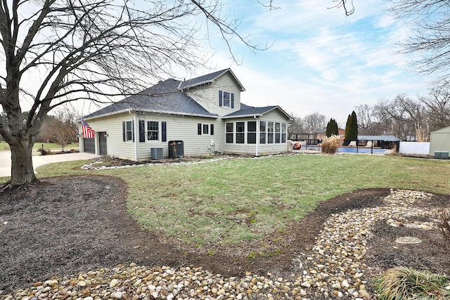 back of property with cooling unit, a yard, and a sunroom