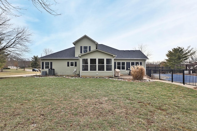 rear view of house with a sunroom, a yard, cooling unit, and a covered pool