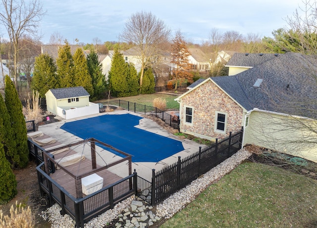 view of swimming pool featuring a storage shed, a yard, and a patio area