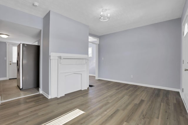 unfurnished living room with a textured ceiling and dark wood-type flooring