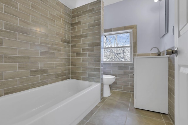 full bathroom featuring tile patterned floors, tile walls, toilet, vanity, and bathtub / shower combination